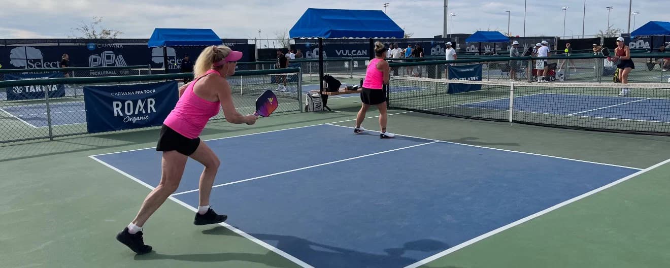 Amateur pickleball players wear bright pink shirts and visors on the pickleball court at Mesa Arizona Cup