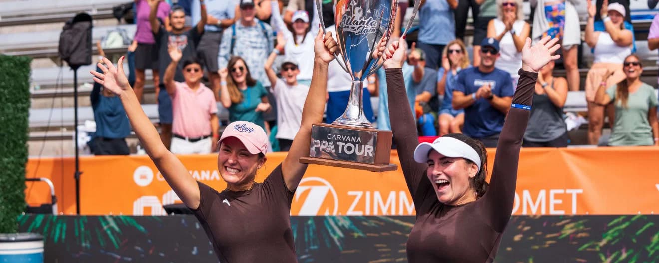 Anna Bright and Rachel Rohrabacher holding their trophy up in the air in victory after their win.